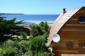 Situated in a lush environment, this cabin offers a view of the ocean and a distant landmass.