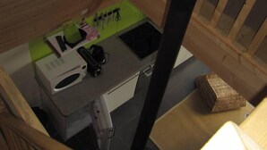 Una kitchenette pequeña equipada con microondas, cafetera y tabla de cortar verde.