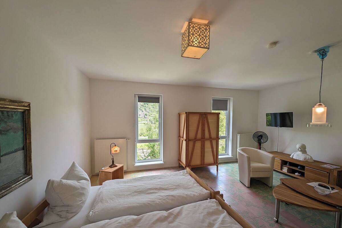 A bedroom with two beds, a desk, a chair, a TV, and a window.