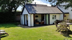 Een klein, laag huis met een puntige dakschild en een veranda.