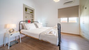 A bedroom with two beds, a bedside table with a lamp, a wardrobe, and a window with a blind. - The Roof - Flat Sea View in Aegina Town (Aegina)