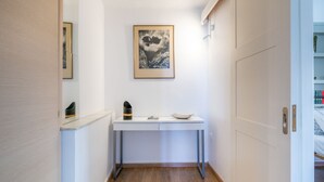 A hallway with a white console table, a framed picture on the wall, and a sliding door leading to another room. - The Roof - Flat Sea View in Aegina Town (Aegina)