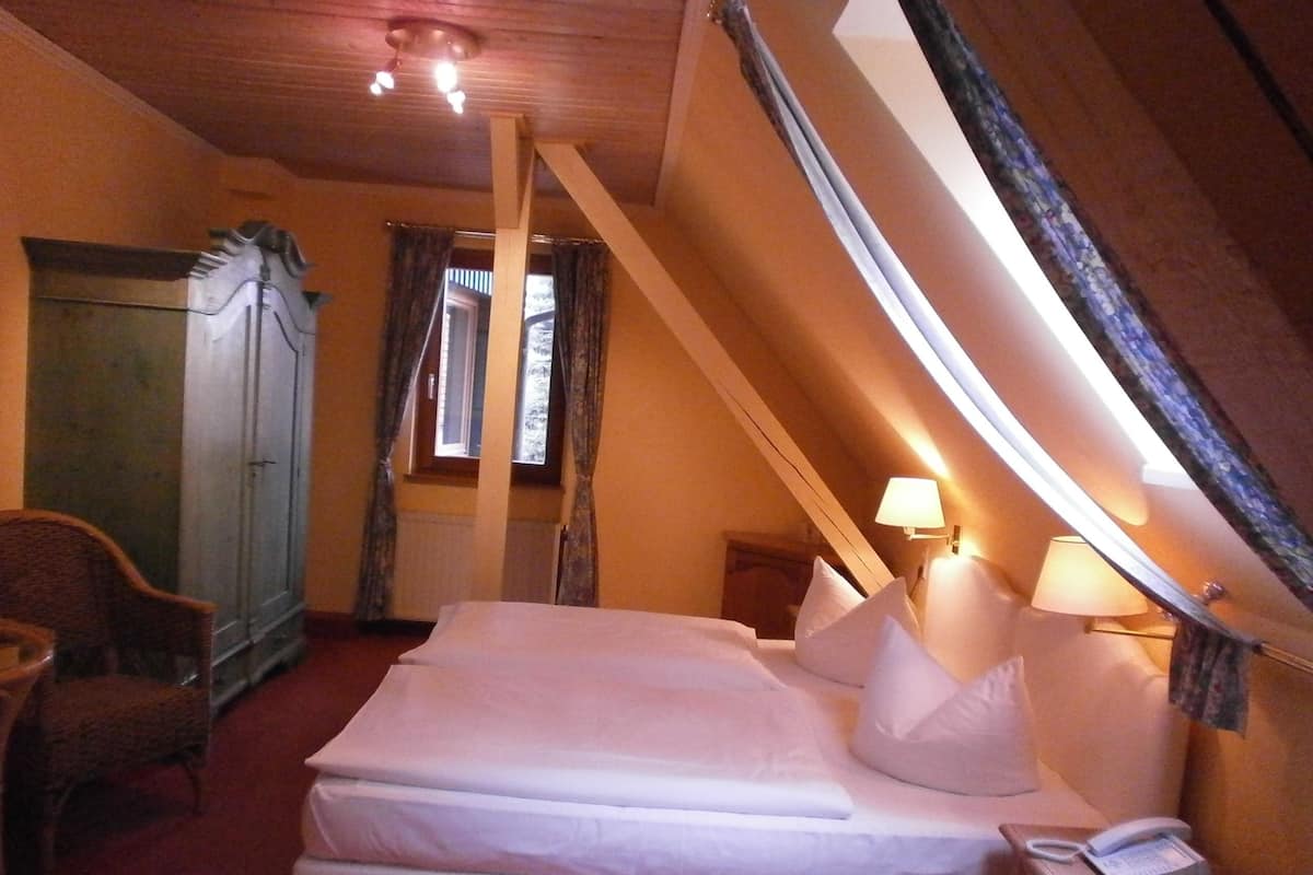 Un dormitorio con cama, una silla, un armario y una ventana.