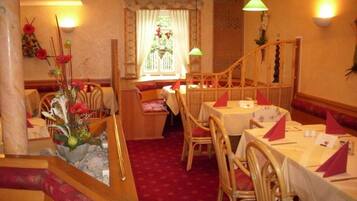 A restaurant with wicker furniture, a red carpet, and a window with curtains.