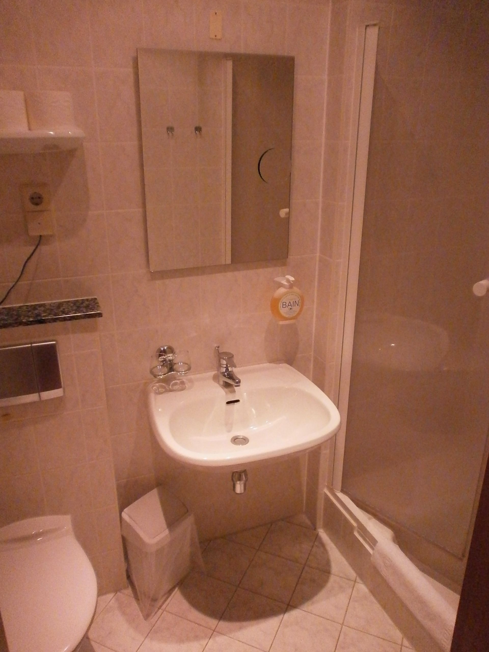 A bathroom with a white sink, mirror, and toilet.