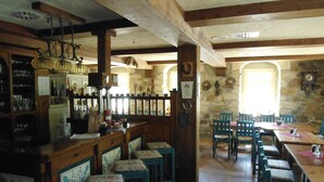 Un interior rústico con barra de madera y zona de estar, paredes de piedra y decoración tradicional.
