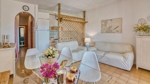 Un salon moderne comprenant un canapé, des fauteuils, une table basse et un coin repas avec une table et des chaises.