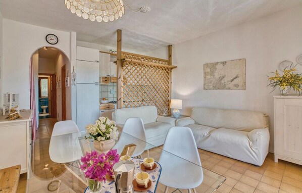 Ein modernes Wohnzimmer mit einer Couch, Sesseln, einem Couchtisch und einem Essbereich mit Tisch und Stühlen.