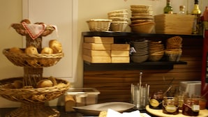 A buffet setup with baskets of bread, jars of condiments, and a variety of dishes on a counter.