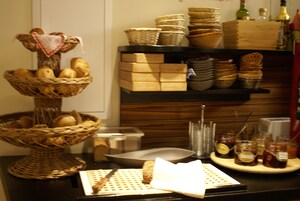 Disposição de buffet com cestas de pão, potes de condimentos e uma variedade de pratos em um balcão.