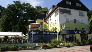 A hotel with a restaurant named 'STORCHEN' on the ground floor, featuring a modern design with a flat roof and large windows.