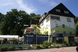 Hotel com restaurante chamado 'STORCHEN' no andar térreo, com design moderno, teto plano e grandes janelas.