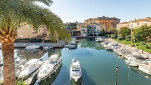 A marina with boats docked, surrounded by buildings and a palm tree. - A (VA022) TH Casa Port Saplaya (Alboraya)