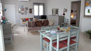 A cozy living room with a sofa, a dining table with chairs, and a television. - Bellissima Campagna Home<br>Pelekapina Chania Crete  (Chania , Crete)
