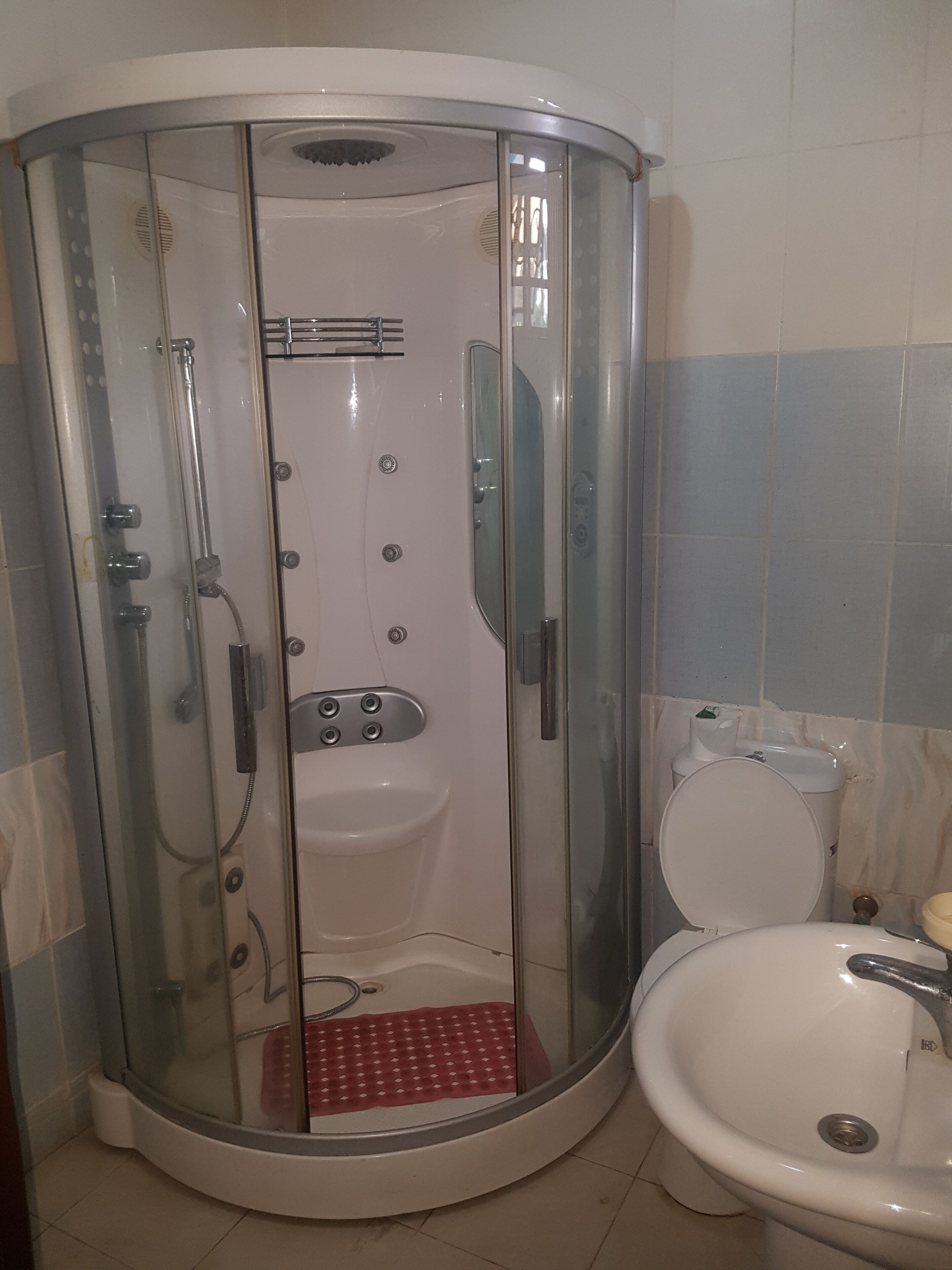 A glass-enclosed shower stall with a built-in sink and toilet.