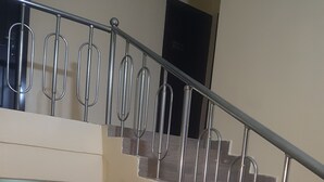 A multi-level interior with a staircase featuring metal railings and a beige wall. - Zeina Suites Abuja (Abuja)