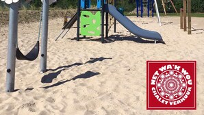 A playground with a slide, climbing structures, and a sand area.