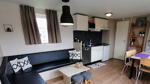 A compact living space with a black sofa, a small dining table, and a kitchenette.