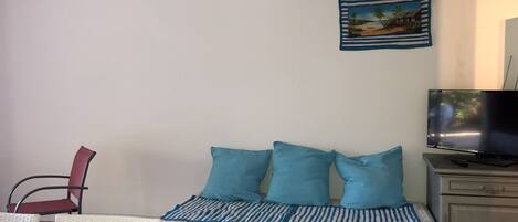 A bedroom with a bed, a TV, a chair, and a painting on the wall.