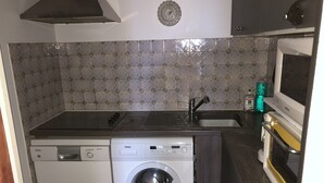 Een kleine keuken met een wasmachine, een magnetron en een spoelbak.
