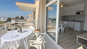 A balcony with a table and chairs, a sliding glass door to a kitchen, and a view of the cityscape. - Agi Rescator 218 Apartamento for rent in Roses Girona. (Roses)
