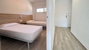 A hotel room with two beds, a ceiling fan, a window, and a door. - Agi Rescator 218 Apartamento for rent in Roses Girona. (Roses)