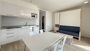 A modern kitchen with white cabinets, a microwave, and a dining area with a table and chairs. - Agi Rescator 218 Apartamento for rent in Roses Girona. (Roses)
