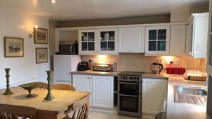 A compact kitchen with white cabinets, a built-in oven, a toaster, and a sink.