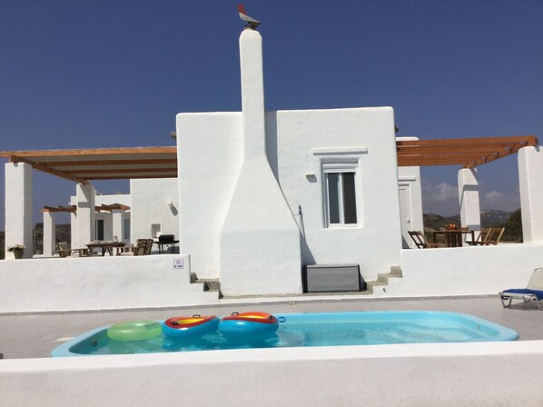 Relax by the serene pool surrounded by a minimalist Mediterranean-style building and outdoor seating.
