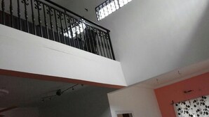 Un interior amb diversos nivells, un balcó, un ventilador de sostre i una porta que condueix a una altra habitació.