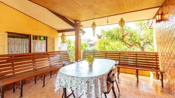 A covered patio area with wooden benches and a round table with a floral tablecloth.