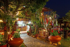 A restaurant with a rustic outdoor setting, including a cobblestone path, wooden benches, and potted plants. - Baan Maihorm Guesthouse (Mae Chan)