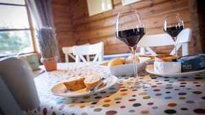 Una mesa de comedor con mantel de lunares, una fuente de pan, una copa de vino tinto y un bol de queso.