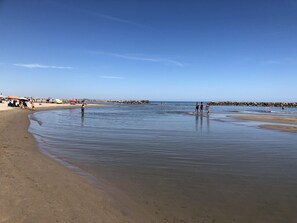 Une plage avec un ciel dégagé, une eau calme et des gens qui profitent du bord de mer.