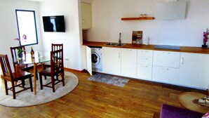 A compact living space with a dining area, a kitchen with a washing machine, and a small seating area. - Relaxing Casa do Atlântico - Funchal (Funchal)