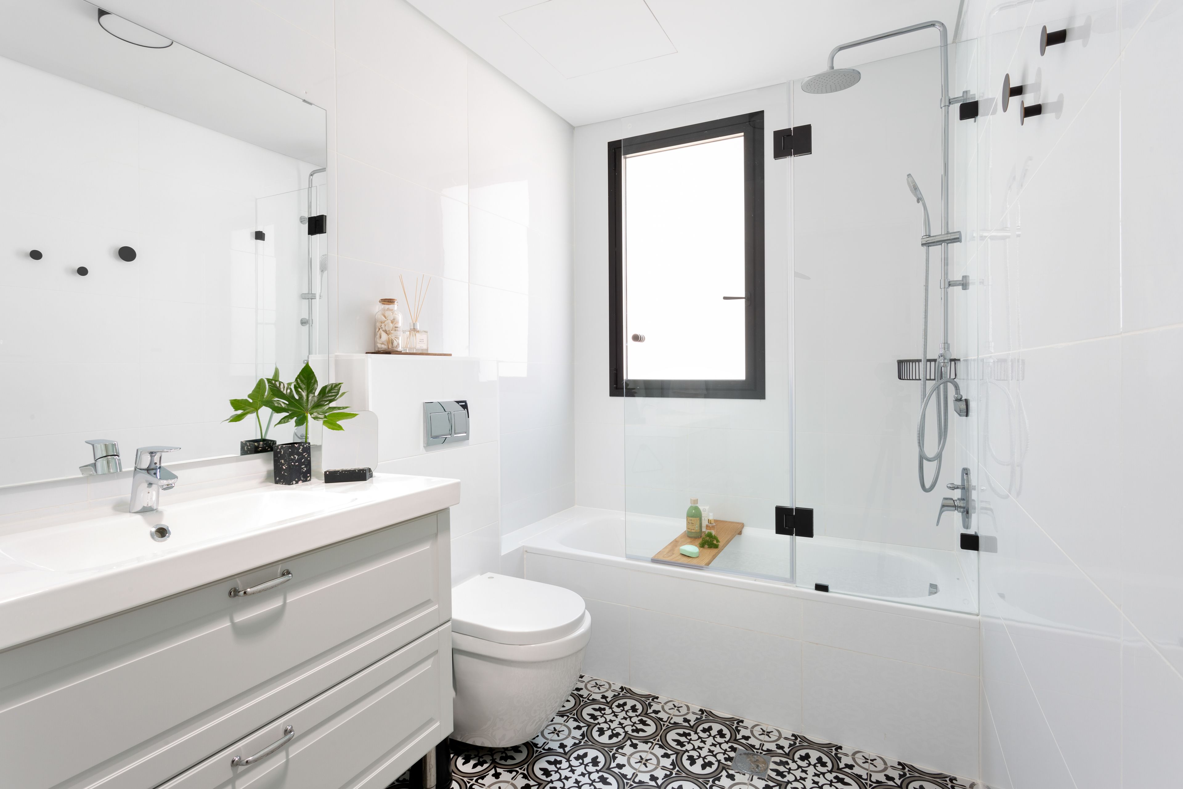 A modern bathroom with a white vanity, a toilet, a bathtub, and a shower area.