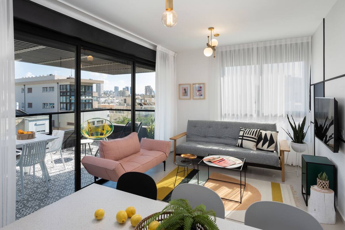 Un salon moderne avec un canapé gris, un fauteuil rose et une table à manger décorée de citrons.