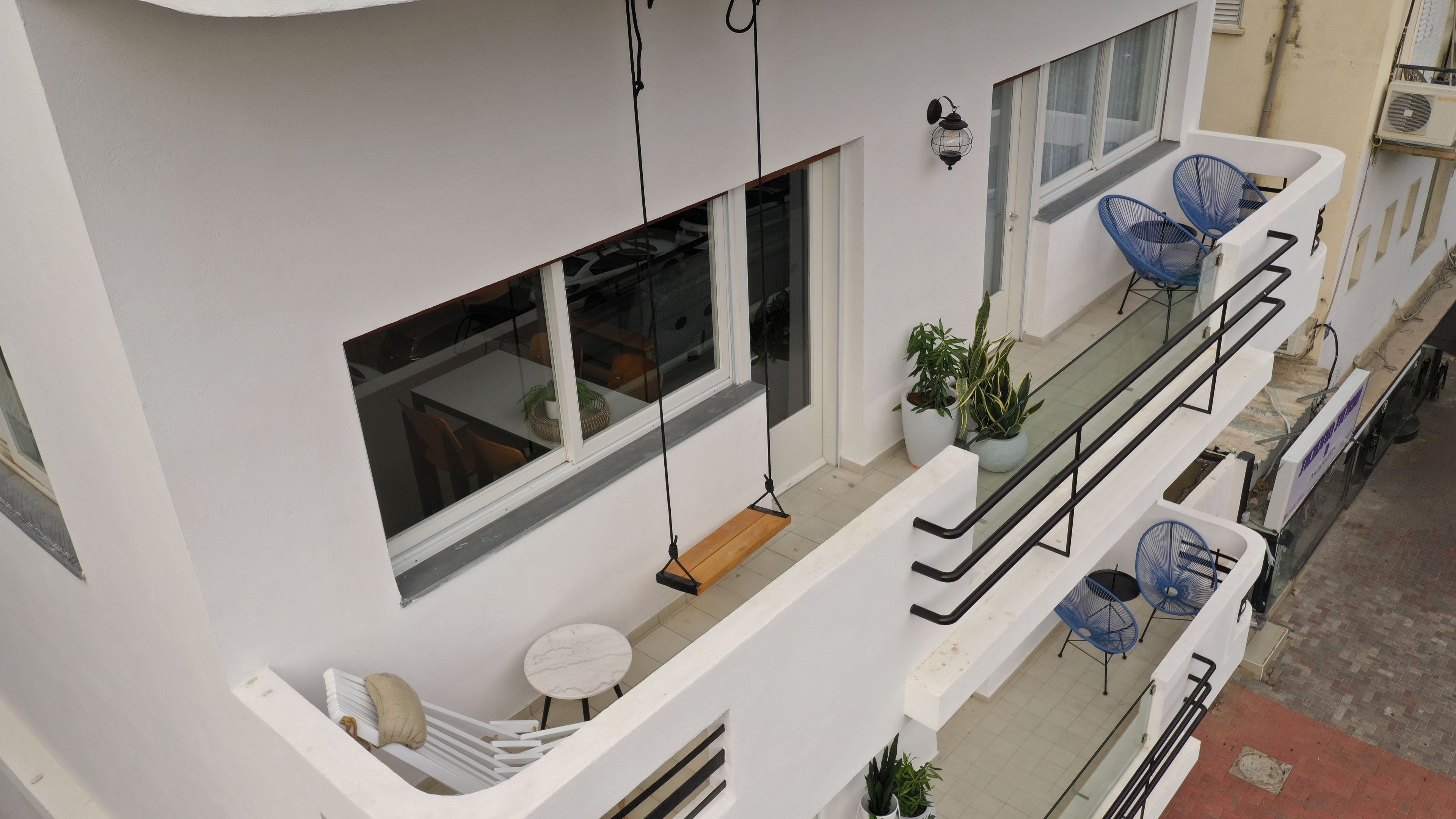 Un apartamento moderno con balcón, una silla colgante y una pequeña mesa con cojín.
