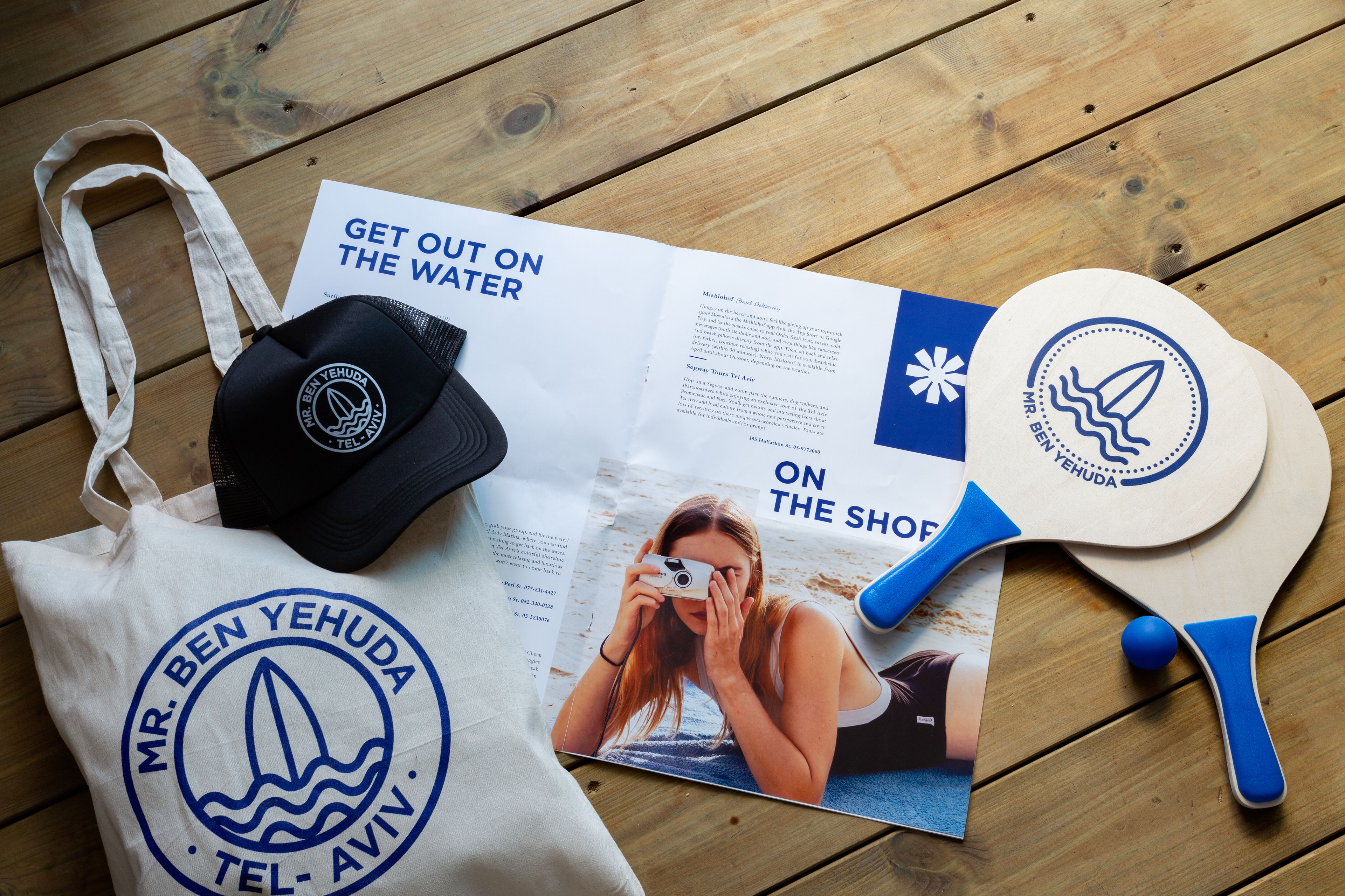 Een brochure, een pet en een peddel op een houten ondergrond.