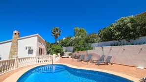 Una piscina con lettini e un camino in pietra.