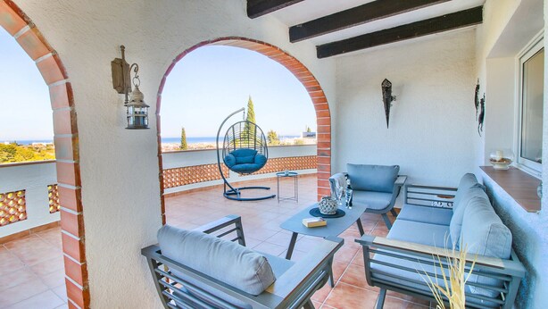 Un balcone con una sedia a dondolo, un divano e un tavolo con bevande.