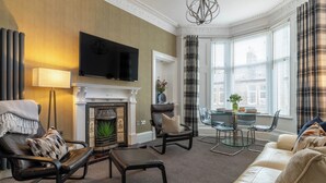 Una sala de estar con chimenea, televisor, sofá y comedor.
