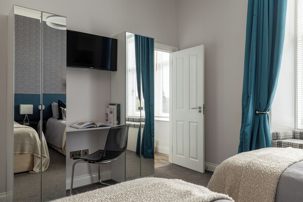 Une chambre à coucher comprenant un lit, un bureau, une chaise, un téléviseur et une armoire.