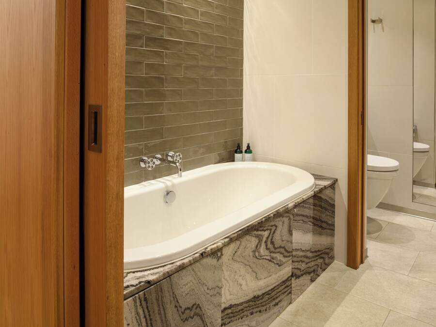 A modern bathroom with a freestanding bathtub, marble countertops, and a tiled shower area.