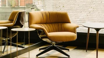 A modern room with a leather armchair, a small round table, and a large window with a brick wall.