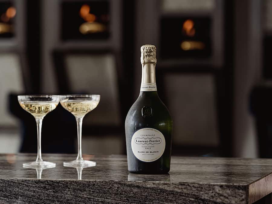 A bottle of champagne and two glasses on a marble surface.