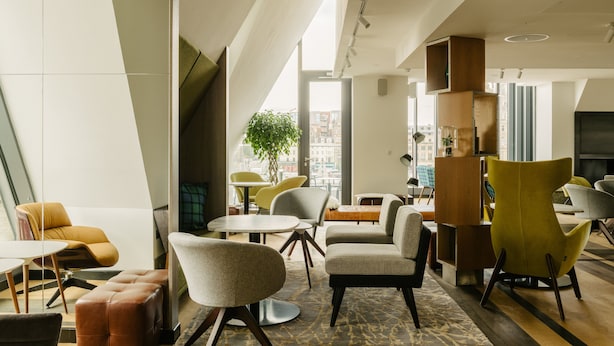 A modern lounge area with contemporary furniture, large windows, and a view of the cityscape. - Market Street Hotel (Edinburgh)