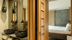 A bathroom with two large, dark stone sinks, a mirror, and a towel rack. - Market Street Hotel (Edinburgh)