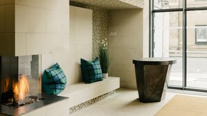 A modern lobby with a fireplace, seating area, and a large window. - Market Street Hotel (Edinburgh)