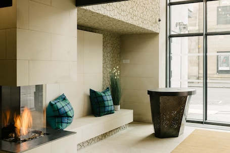 A modern lobby with a fireplace, seating area, and a large window.
